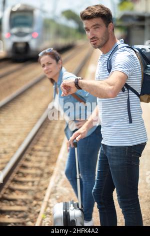 Mann, der die Zeit auf der Armbanduhr am Bahnhofssteig überprüft Stockfoto