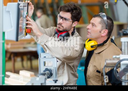 Junge Arbeiter drücken Steuerungen für Werkstattmaschinen Stockfoto
