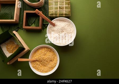 Schalen mit weißem Reis und gelben Mungbohnen und Holzformen für die Herstellung von klebrigen Reiskuchen für Tet Feiertagsfeier vorbereitet Stockfoto