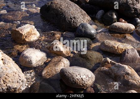 Natursteine in verschiedenen Größen im Meer. Nahaufnahme. Stockfoto