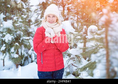 Glückliche Frau in roter Jacke posiert für Foto im Winterwald Stockfoto