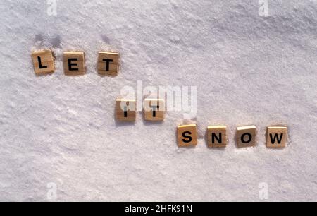 Lassen Sie es Schnee Phrase auf einem weißen sauberen Schnee. Es soll Schnee auf den Schnee mit hölzernen Buchstaben geschrieben werden. Stockfoto