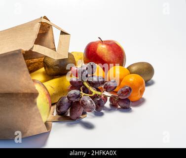 Einkaufen und Lieferung von gesunden Lebensmitteln auf weißem Hintergrund. Gesundes veganes vegetarisches Essen in einer Papiertüte. Gesunde Ernährung gegen Covid Stockfoto