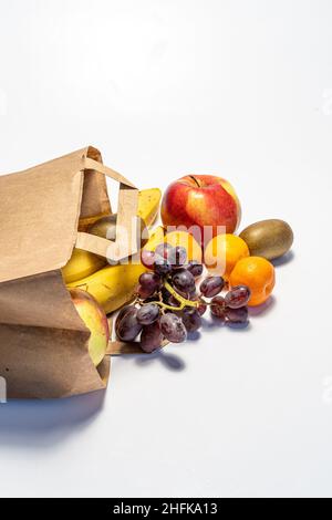 Einkaufen und Lieferung von gesunden Lebensmitteln auf weißem Hintergrund. Gesundes veganes vegetarisches Essen in einer Papiertüte. Gesunde Ernährung gegen Covid Stockfoto