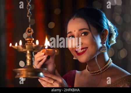 Schöner indischer Wonam blitzen eine Lampe mit Diya anlässlich von Diwali Stockfoto