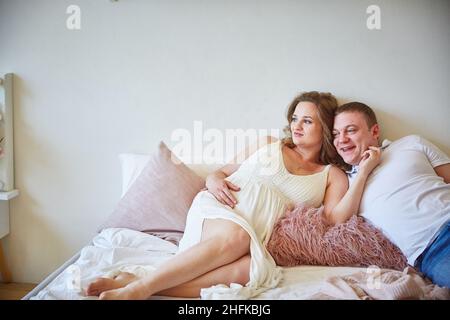 Junge Familie auf dem Bett im Schlafzimmer. Stockfoto