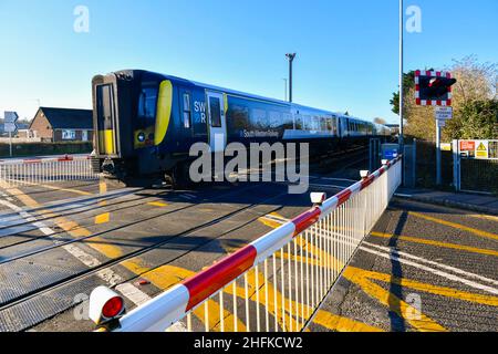 Wool, Dorset, Großbritannien. 17th. Januar 2022. Ein Zug der South Western Railway am Bahnübergang Wool Station in Dorset als neuer temporärer Fahrplan mit stündlichen Verbindungen beginnt heute auf der Strecke Weymouth nach London Waterloo, ohne direkte Züge nach London und umgekehrt nach Weymouth, da die Covid 19 Omicron-Variante zu Personalmangel führt. Reisende müssen nun in Bournemouth den Zug wechseln, um weiter zu ihren Zielen zu fahren. Bildnachweis: Graham Hunt/Alamy Live News Stockfoto