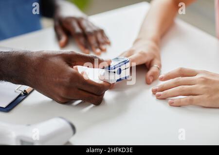 Nahaufnahme eines nicht erkennbaren Arztes, der die Sauerstoffsättigung misst, während er den Patienten in der medizinischen Klinik konsultiert, Platz kopieren Stockfoto