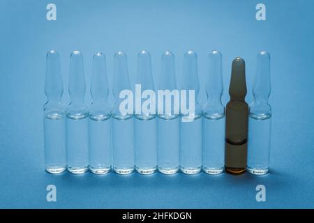 Medizinische Ampullen stehen auf dem Tisch, eine davon in einer anderen Farbe. Stockfoto