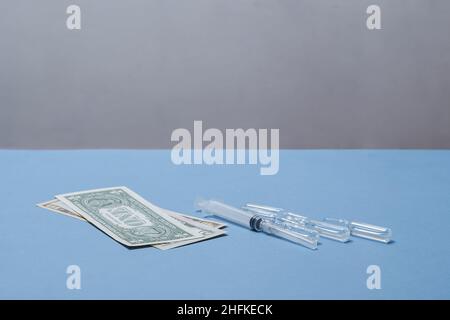 Geld, eine Spritze und Ampullen stehen auf dem Tisch. Stockfoto