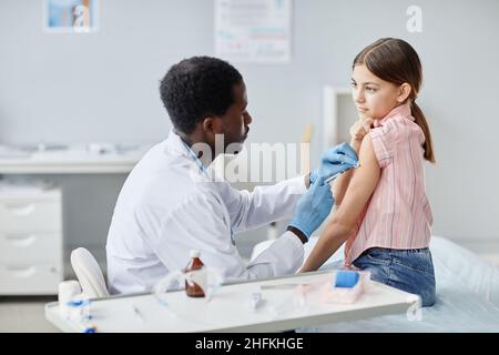 Porträt eines mutigen kleinen Mädchens, das gegen COVID geimpft wird - 19 in der Kinderimpfklinik Stockfoto