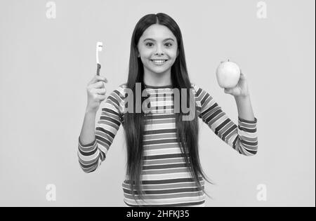 Mundhygiene beachten. Glückliches Mädchen halten Apfel und Zahnbürste. Mundhygiene. Zahnpflege Stockfoto