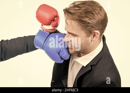 Junge professionelle Geschäftsleute werden mit einem Boxhandschuh, der auf weißem, lockerem Material isoliert ist, ins Gesicht geschlagen Stockfoto