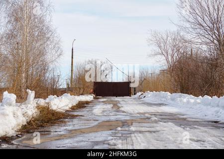 Eiserne Tore und eine Barriere auf einer alten verlassenen Straße. Sperrgebiet Stockfoto