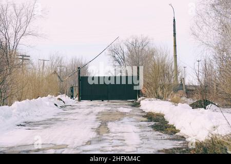 Eiserne Tore und eine Barriere auf einer alten verlassenen Straße. Sperrgebiet Stockfoto