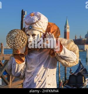 Ein Wahrsager und Harlekin oder arlecchino in ausgefallenen Kostümen an der Lagune beim Karneval in Venedig, in der Karnevalsstadt von Venedig, Italien Stockfoto