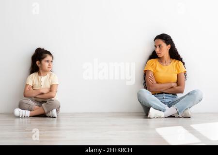 Konflikte Mit Der Mutter Tochter. Beleidigt Kleines Mädchen Und Mutter Sitzen Auseinander Auf Dem Boden Stockfoto