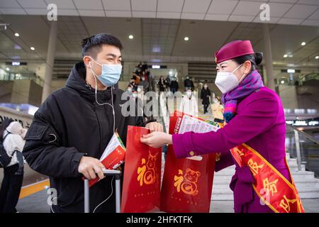 (220117) -- CHONGQING, 17. Januar 2022 (Xinhua) -- Ein Mitarbeiter verteilt Neujahrsgeschenke mit dem chinesischen Schriftzeichen „Fu“, was auf Englisch viel Glück bedeutet, an einen Passagier am Chongqing Nordbahnhof in Chongqing, Südwest-China, am 17. Januar 2022. Die chinesische Reisesaison für das Frühlingsfest 2022 wird voraussichtlich 1,18 Milliarden Fahrgastreisen verzeichnen, ein Anstieg von 35,6 Prozent im Vergleich zum Vorjahr, aber 20,3 Prozent weniger als im Jahr 2020, teilte das Verkehrsministerium mit. Die 40-tägige Reisesaison, auch bekannt als chunyun, begann am Montag und viele Menschen werden reisen, um sich mit ihren Familien zum Lunar zu vereinen Stockfoto