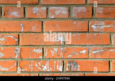 Alte orangefarbene Ziegelmauer. Lackierte Wandoberfläche mit verwaschener Kleidung. Vintage rote Ziegelwand mit Anzeichen von alten Anzeigen darauf. Urban Foto Hintergrund für Design Stockfoto