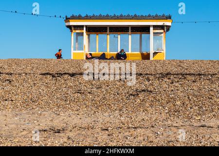 Ein Paar entspannt sich in der Sonne in einem denkmalgeschützten Strandhaus an der Clarence Esplanade, Southsea Hampshire. Stockfoto