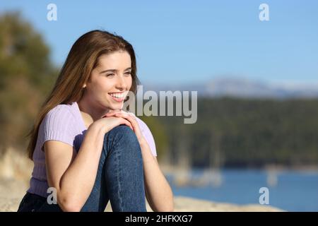 Glückliche Frau, die Aussicht in einem wunderschönen See betrachtet Stockfoto