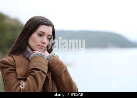 Nachdenkliche Frau im Winter, die in einem See denkt und nach unten schaut Stockfoto