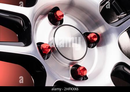 Rote Radschrauben oder Muttern an Leichtmetallrädern, Nahaufnahme mit einer Kappe. Auto Tuning Detail leere Kappe auf Farbverlauf roten Hintergrund. Stockfoto