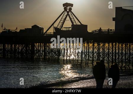 Am South Parade Pier spazieren 2 Menschen entlang des Strandes, der gegen den Sonnenuntergang in Southsea, Hampshire, geschildet wird. Stockfoto