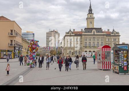 Novi Sad, Serbien - 21. September 2021: Menschen gehen an der Fußgängerzonen-Straße und dem Rathaus im Stadtzentrum. Stockfoto