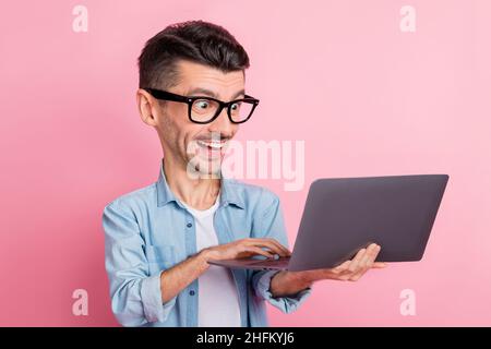 Portrait von schönen fröhlich großen lustigen Gesicht Kerl in den Händen mit Laptop isoliert über rosa Hintergrund halten Stockfoto