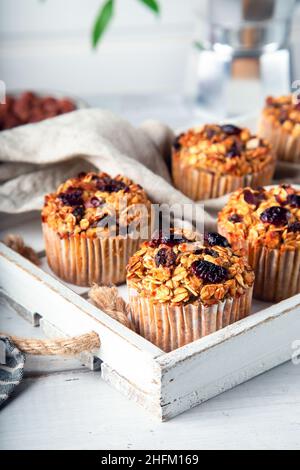 Frische hausgemachte Haferflocken-Muffins mit getrockneter Cranberry auf weißem Holztablett. Gesundes glutenfreies Dessert. Nahaufnahme. Stockfoto