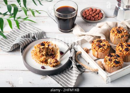 Frische hausgemachte Haferflocken-Muffins mit getrockneter Cranberry auf weißem Holztablett. Gesundes glutenfreies Dessert. Stockfoto