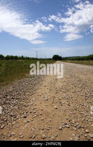 Die typischen staubigen Schotterstraßen in der Toskana in Italien mit einer schönen Natur und Landschaft rund um und alte Häuser herum. Stockfoto