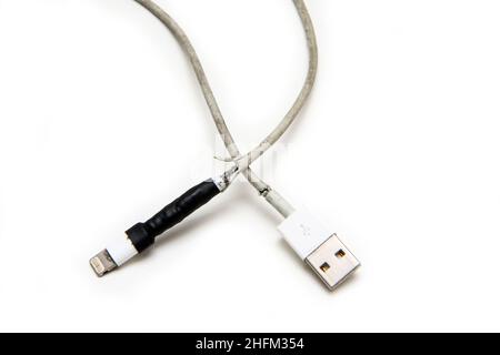 Das Detail eines Smartphones Ladegerät mit gebrochenem und ausgefranstem Kabel. Schon einmal mit Band fixiert, aber wieder gebrochen. Typisches Problem der Benutzer. Stockfoto