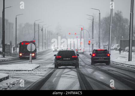 Perspektivische künstlerische Ansicht einer Straße während eines Schneesturms, mit roten Ampeln von Autos und Ampeln Stockfoto