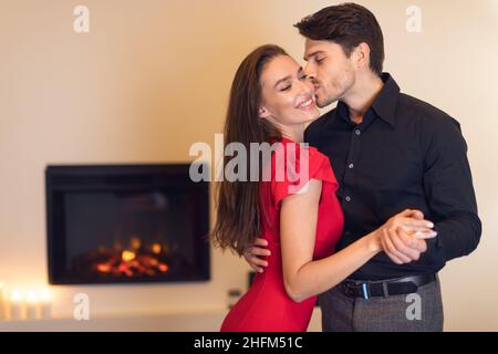 Lächelnder fröhlicher Kerl, der seine hübsche Frau küsst Stockfoto