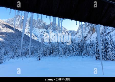 Eiszapfen vom Chaletdach in der Winterlandschaft im Krnica-Tal, Slowenien Stockfoto