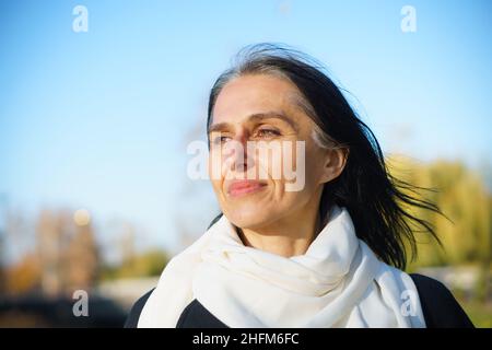 Profil Seitenansicht Porträt einer attraktiven, fröhlichen, verträumten, grauhaarigen Frau mittleren Alters, die sich an sonnigen Tagen im Freien entspannt Stockfoto