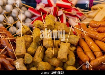 Auswahl an thailändischen Speisen auf einem Lebensmittelmarkt auf der Insel phuket in thailand, Snacks und Buffetspeisen auf einem Street Food Stand in thailand. Stockfoto