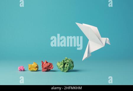 Bunte zerknitterte Papierkugeln mit einer Origami-Papiertaube, Frieden, Freiheit, Vielfalt oder Chancenkonzept auf blauem Hintergrund Stockfoto