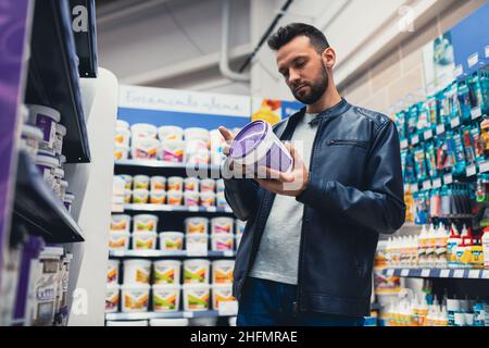 Ein Mann in einem Baumarkt wählt Farbe für Reparaturen im Haus Stockfoto