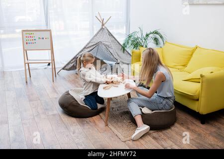 Kind und Mutter spielen Holzklötze Spiel in der Nähe der Couch und Tipi zu Hause Stockfoto