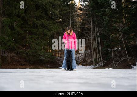 Hundegehorsam-Trainerin arbeitet mit ihrem labrador Retriever Hund, der draußen in der Winternatur zwischen ihren Beinen steht. Stockfoto