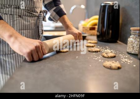 Männliche Hände Nivellierung Oberfläche von rohem Cookie mit Nudelholz Stockfoto