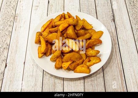 Teller voll mit Kartoffeln in Keile auf Holztisch geschnitten Stockfoto