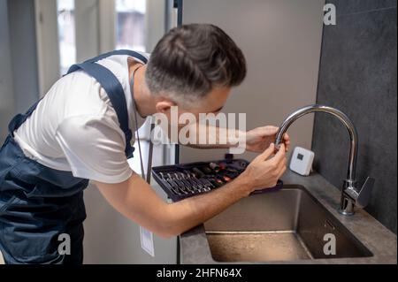 Mann dreht Wasserhahn Belüfter auf Ausguss-Rohr Stockfoto