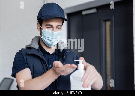 Entgegennahme Mann in medizinischer Maske Anwendung verschwommenes Händedesinfektionsmittel im Büro Stockfoto