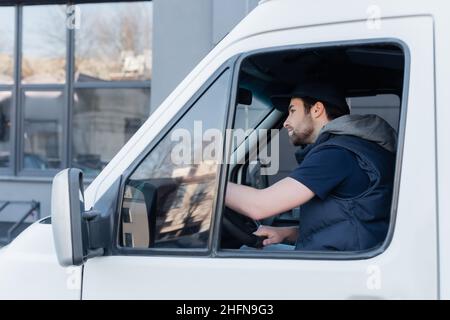 Seitenansicht des jungen Kuriers in uniform fahrenden Autos Stockfoto