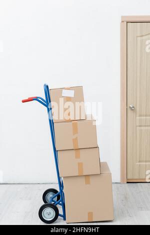 Pappkartons auf dem Wagen neben der Tür im Flur Stockfoto