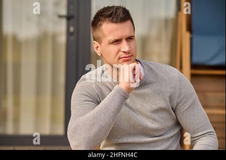 Mann in der Nähe des Hauses, der nachdenklich zur Seite schaut Stockfoto